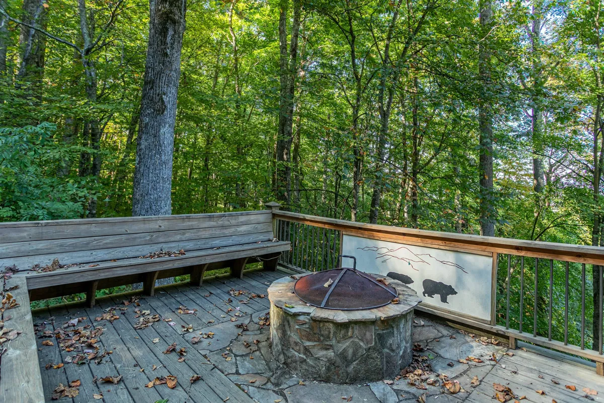 A dedicated fire pit area surrounded by wooden seating, nestled among tall trees. The setup encourages group gatherings and provides a cozy focal point for storytelling or roasting marshmallows under the stars.