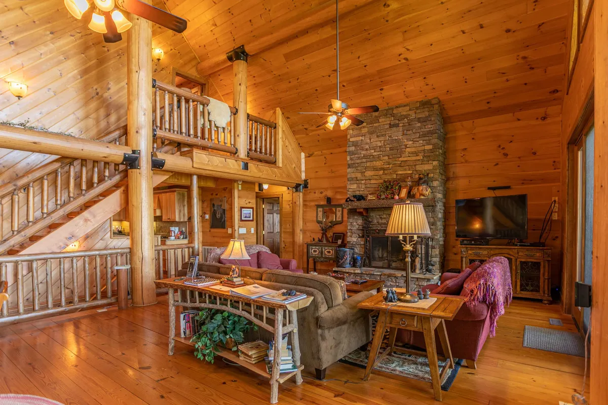 A warm and welcoming living area featuring a striking stone fireplace, exposed wooden beams, and plush seating, creating a perfect setting for intimate gatherings or romantic evenings by the fire.