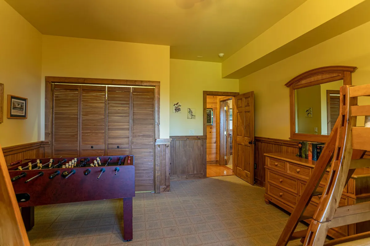 This image highlights a foosball table set against wooden paneling, with a dresser and an open doorway leading to another cozy room. The ambiance is playful yet intimate, ideal for friendly competitions and shared laughter.